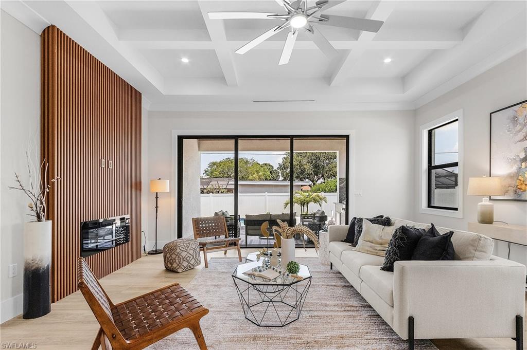 Living room with coffered ceiling, ceiling fan, light wood finished floors, and recessed lighting