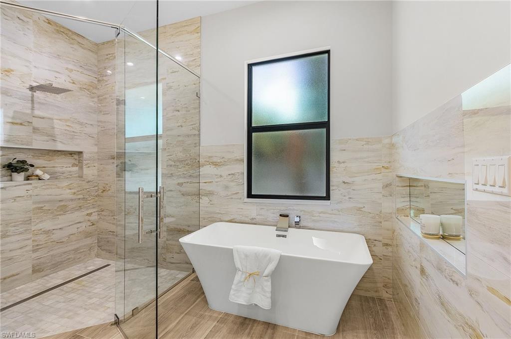 Full bath with a stall shower, a freestanding bath, and tile walls