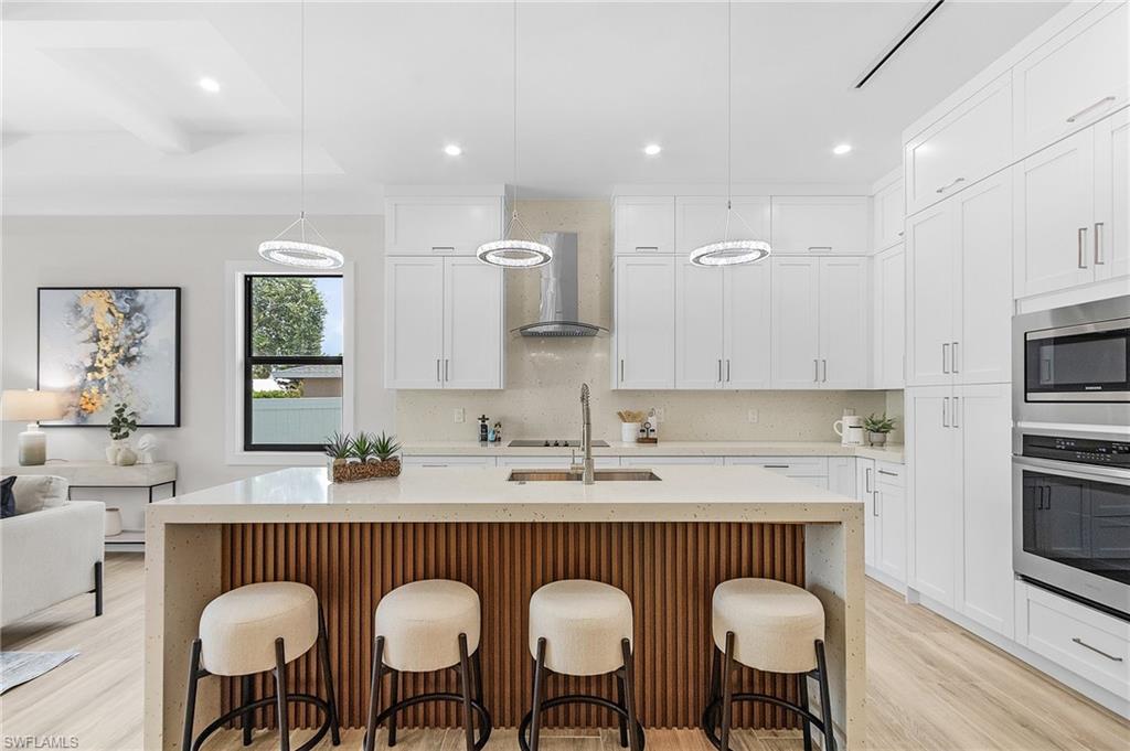 Kitchen featuring light stone counters, stainless steel appliances, a kitchen breakfast bar, and white cabinetry