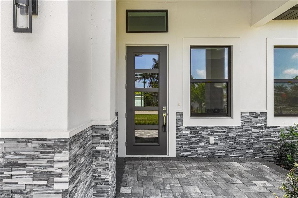 Doorway to property featuring stone siding, a patio, and stucco siding