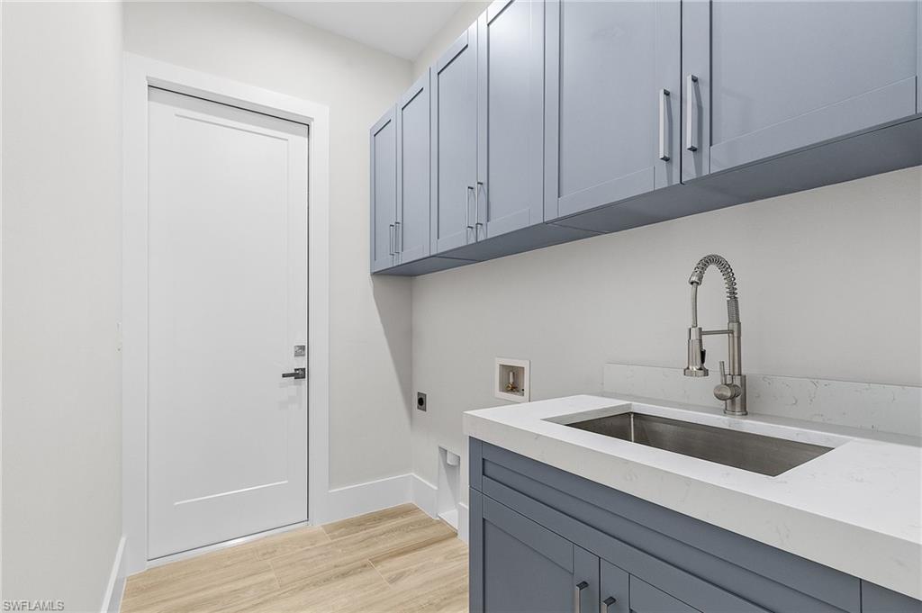 Laundry room with electric dryer hookup, light wood-style flooring, hookup for a washing machine, and cabinet space