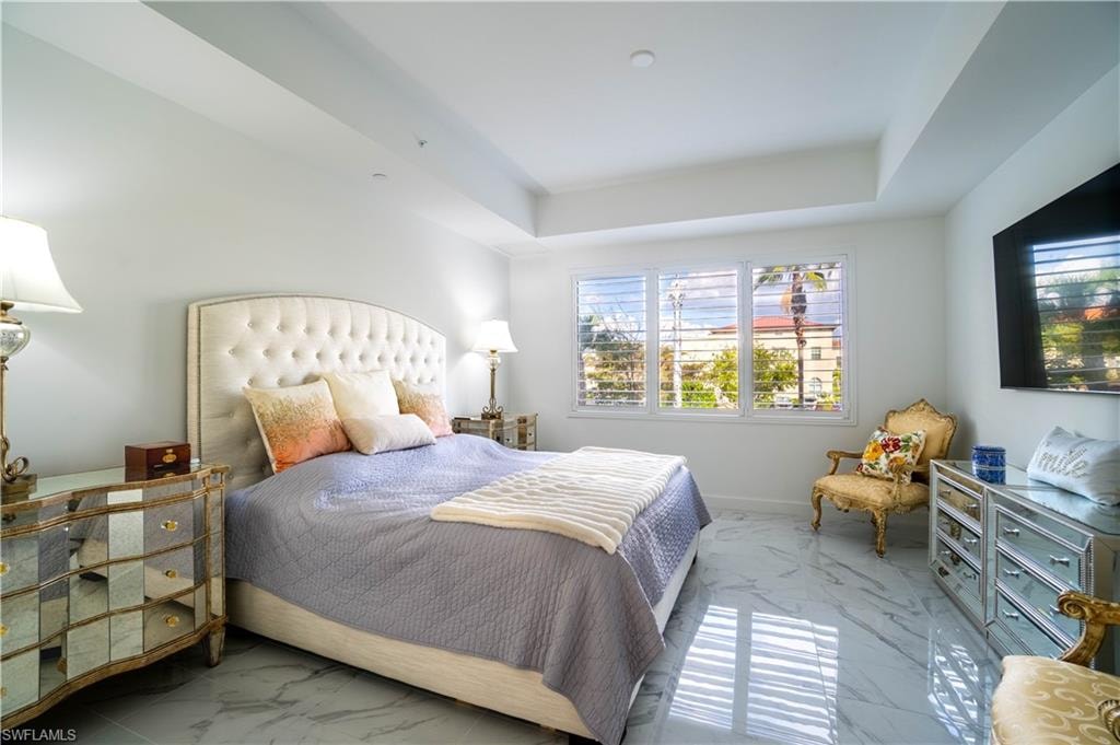 Bedroom with light marble finish flooring and a raised ceiling