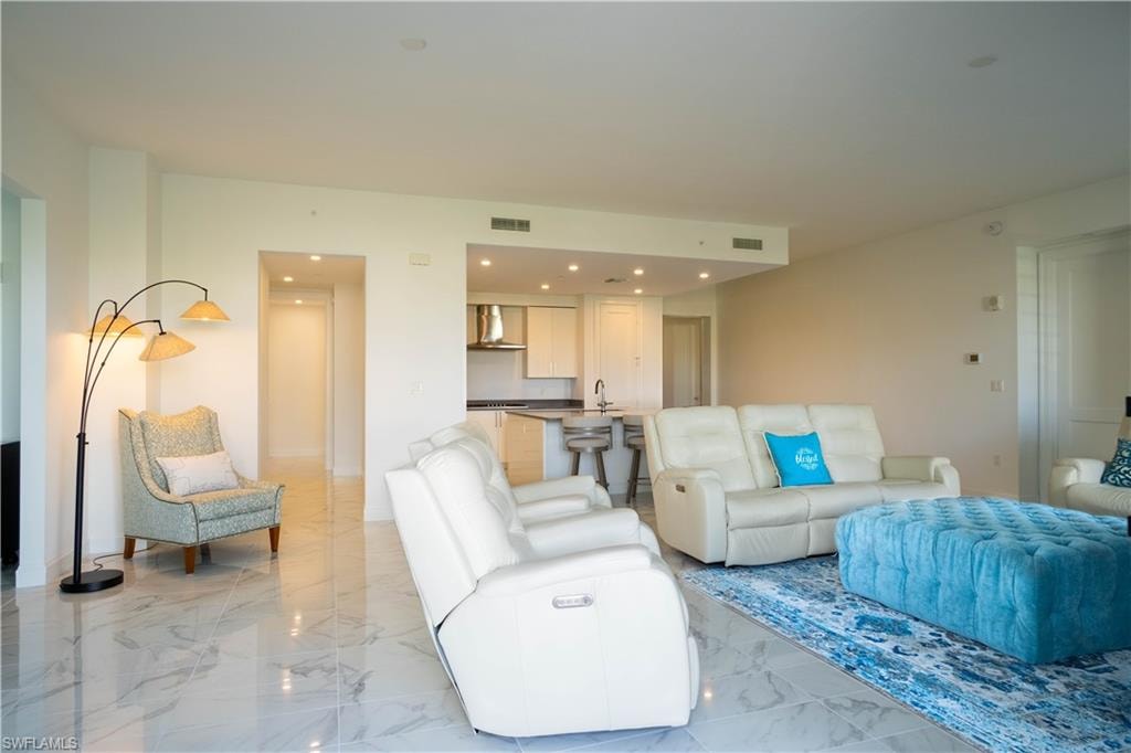 Open-concept living space featuring high ceilings, white wall finishes, and large format marbled-finish flooring