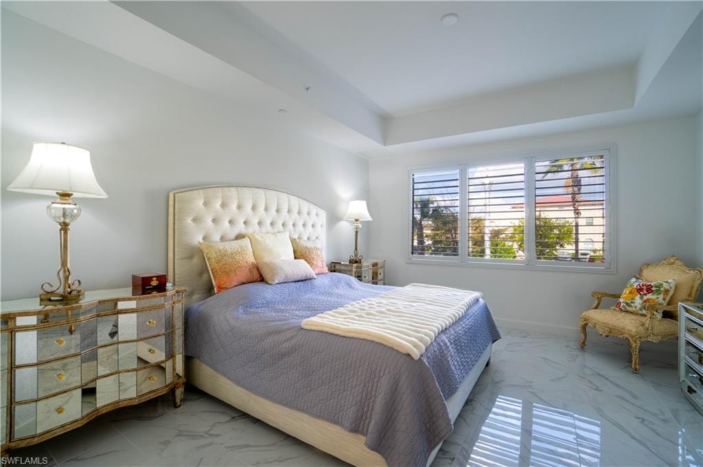 Bedroom featuring light marble finish flooring and a tray ceiling