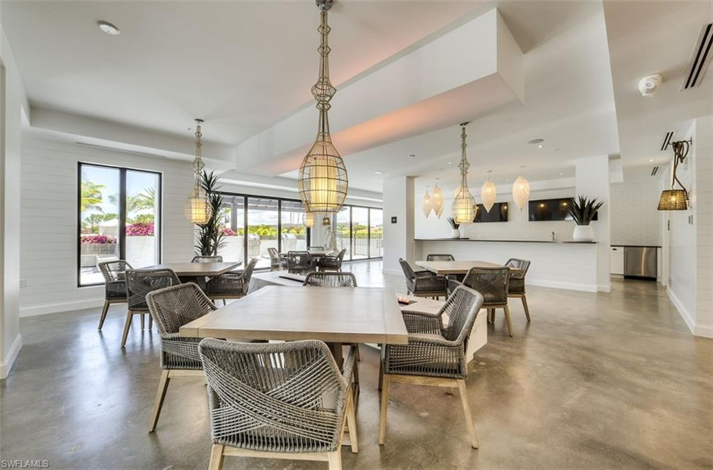 Interior gathering space featuring concrete-finish flooring, multiple dining areas, and a service bar with stainless steel appliances