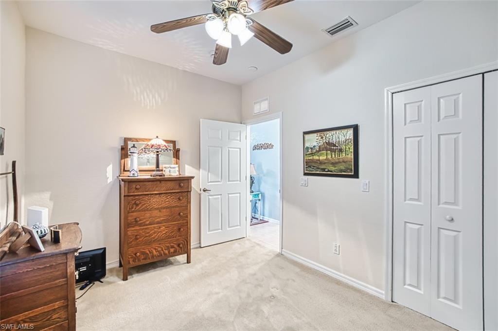Bedroom featuring light carpet, a ceiling fan, and a closet