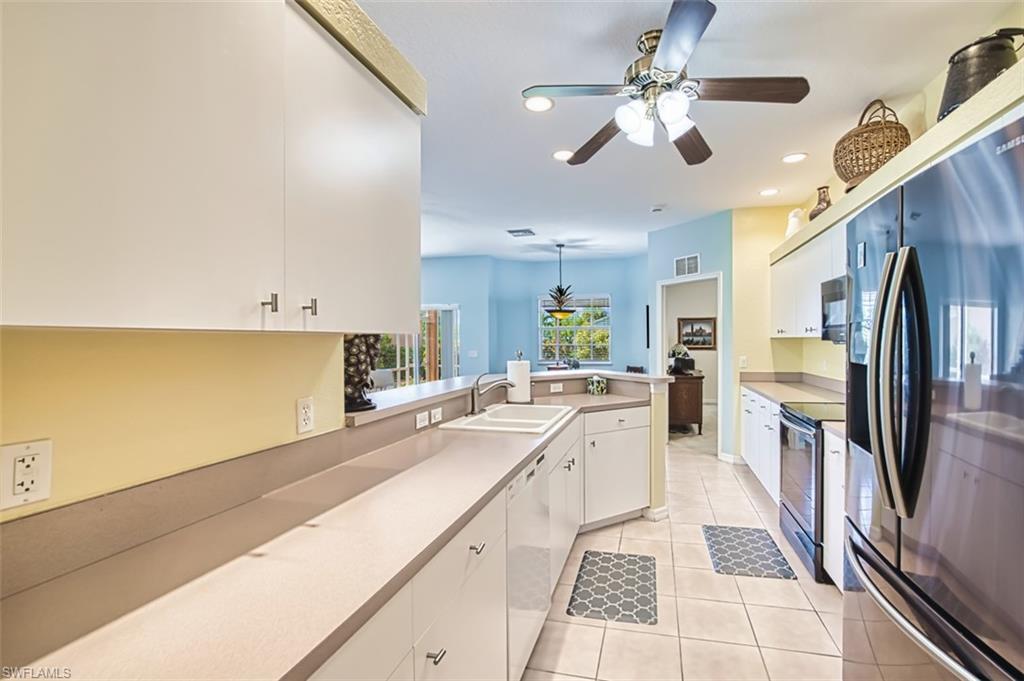 Kitchen with fridge with ice dispenser, stainless steel range with electric stovetop, light countertops, light tile patterned flooring, and white dishwasher