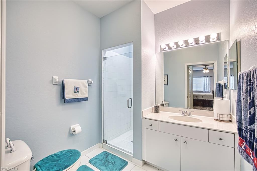 Bathroom with a shower stall, vanity, a textured wall, light tile patterned flooring, and ceiling fan