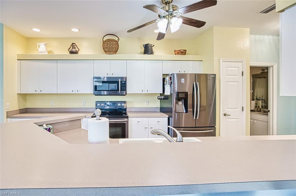 Kitchen with stainless steel appliances, light countertops, white cabinetry, a ceiling fan, and recessed lighting