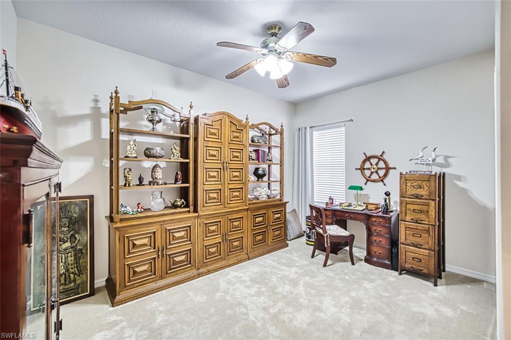Office space featuring light colored carpet, ceiling fan, and a fireplace
