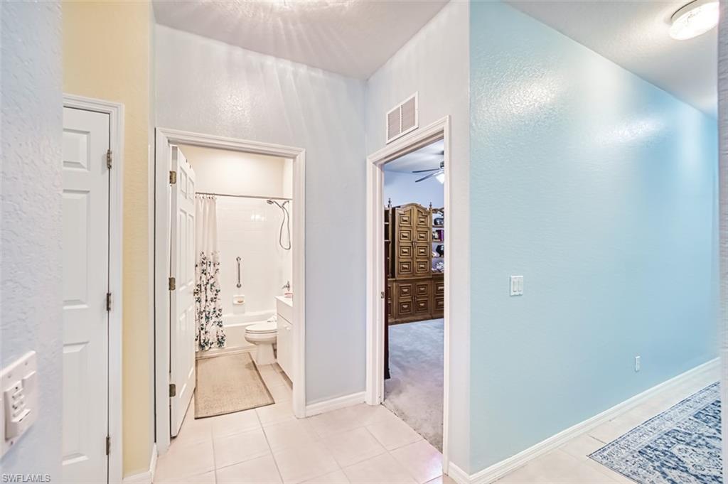 Hallway featuring light tile patterned floors and a textured wall