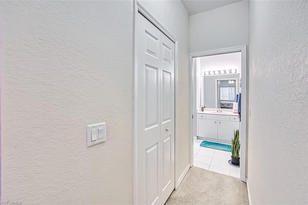 Hallway featuring a textured wall and light colored carpet