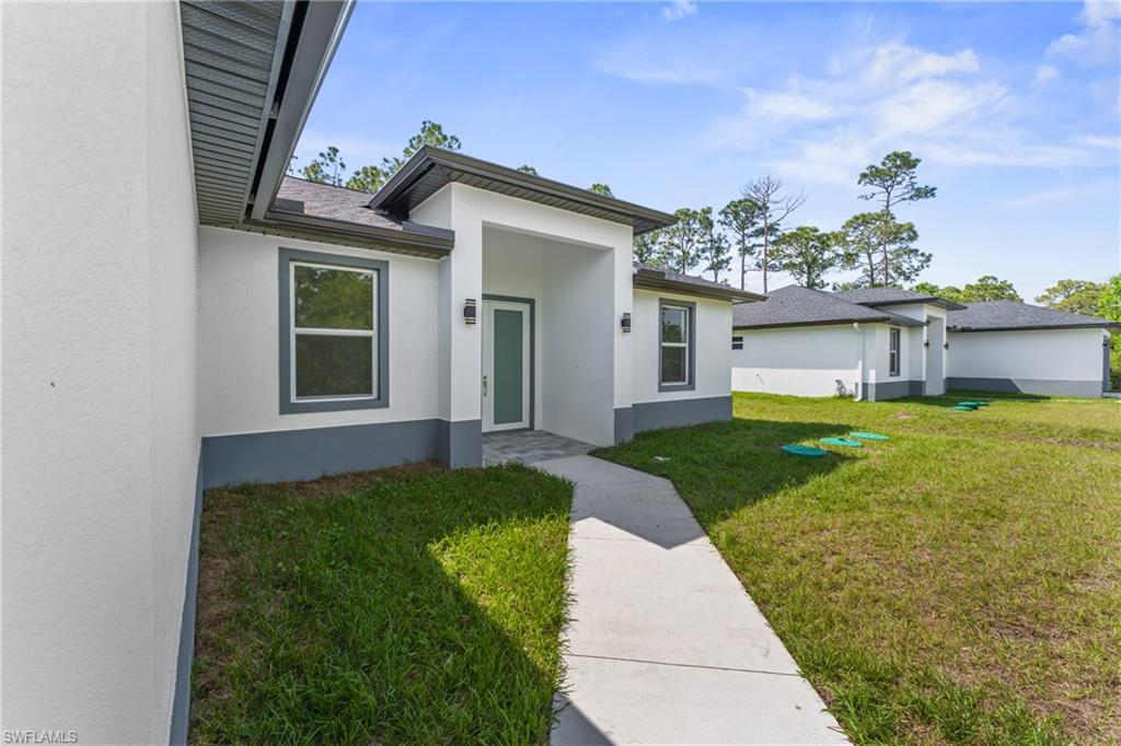 Doorway to property with a lawn and stucco siding