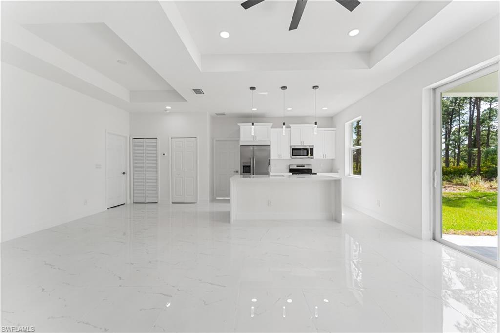 Unfurnished living room with marble finish floor, recessed lighting, a raised ceiling, visible vents, and a ceiling fan