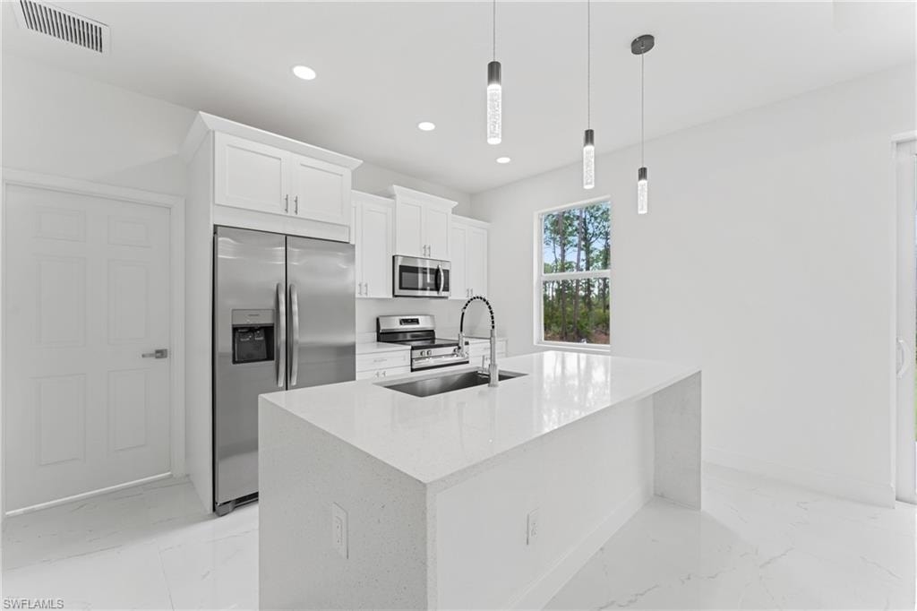 Kitchen with marble finish floor, visible vents, appliances with stainless steel finishes, white cabinets, and a sink