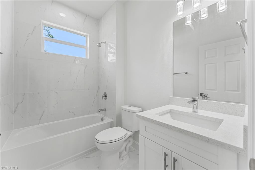 Full bath featuring marble finish floor,  shower combination, vanity, and toilet
