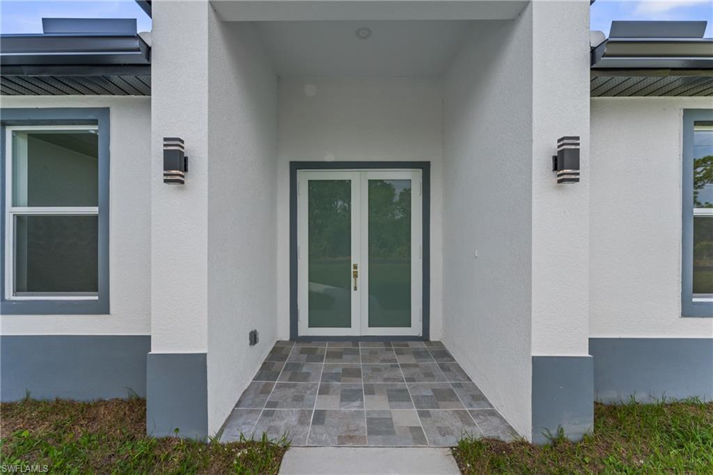 Property entrance with a standing seam roof, metal roof, french doors, and stucco siding