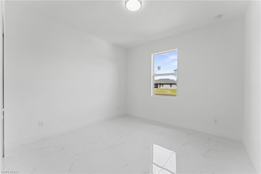 Spare room featuring marble finish floor and baseboards