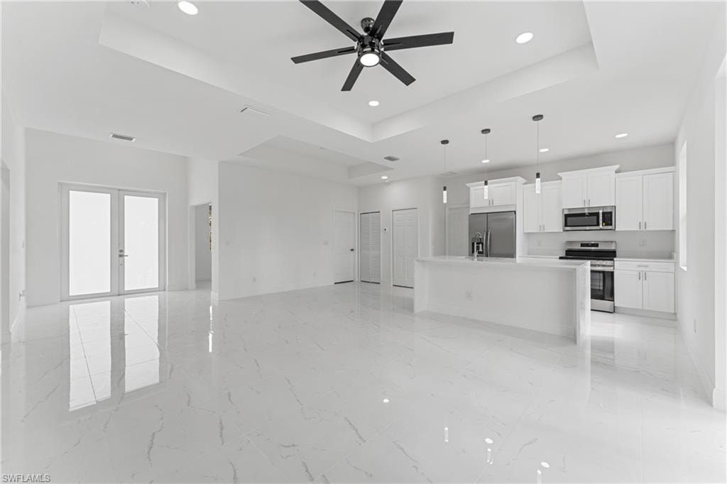 Unfurnished living room featuring french doors, recessed lighting, a raised ceiling, visible vents, and ceiling fan