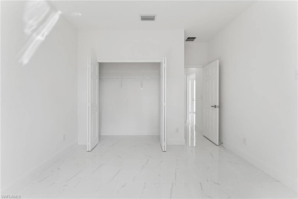 Unfurnished bedroom featuring a closet, marble finish floor, visible vents, and baseboards