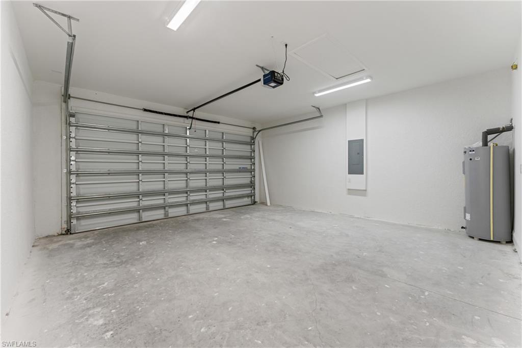 Garage featuring electric panel, water heater, and a garage door opener