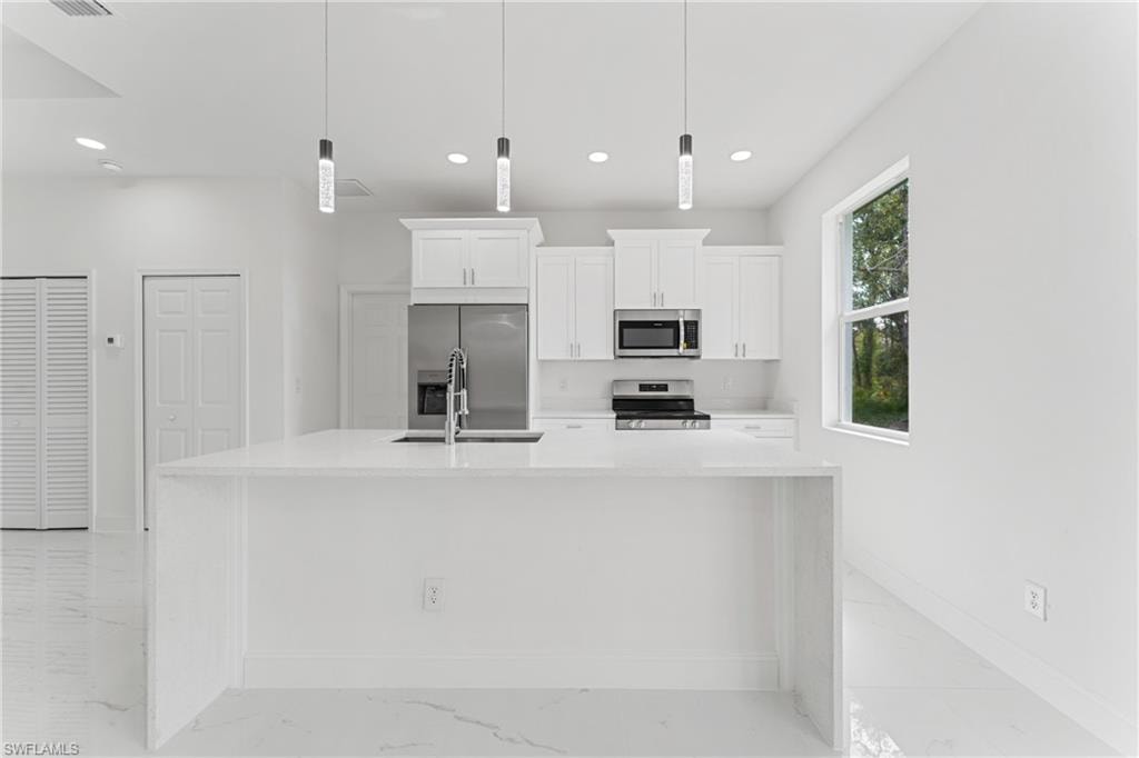 Kitchen featuring white cabinets, appliances with stainless steel finishes, marble finish floor, light countertops, and recessed lighting