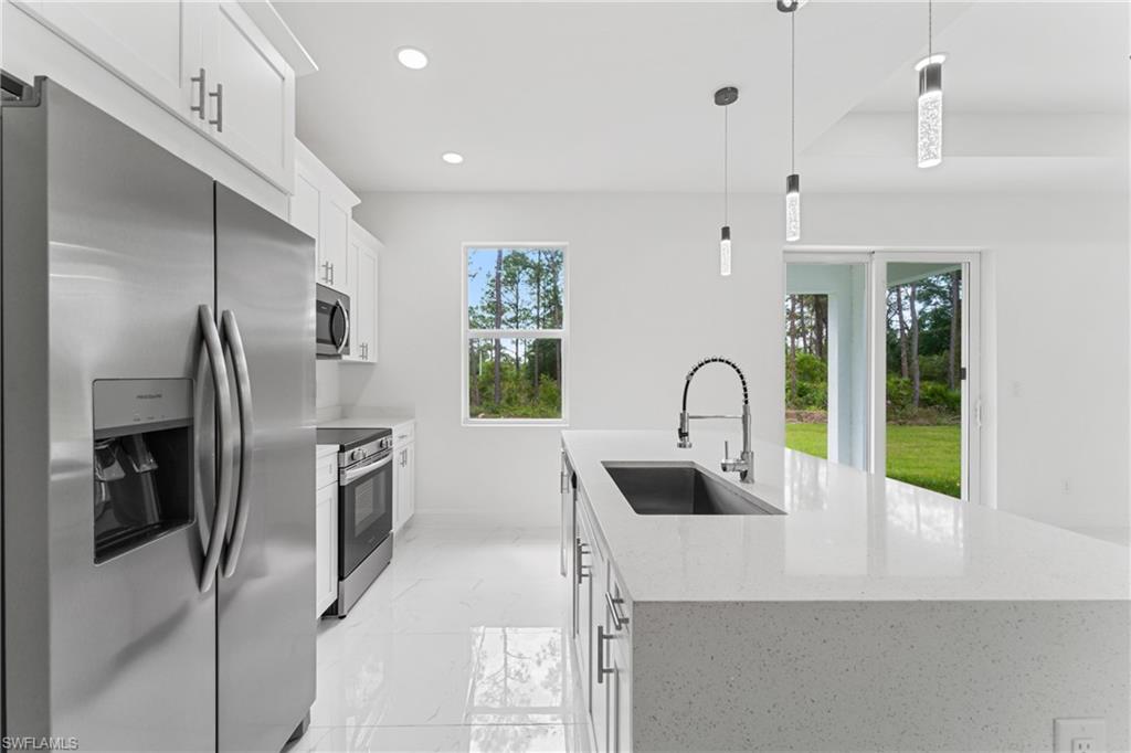 Kitchen with a kitchen island with sink, recessed lighting, a sink, marble finish floor, and appliances with stainless steel finishes