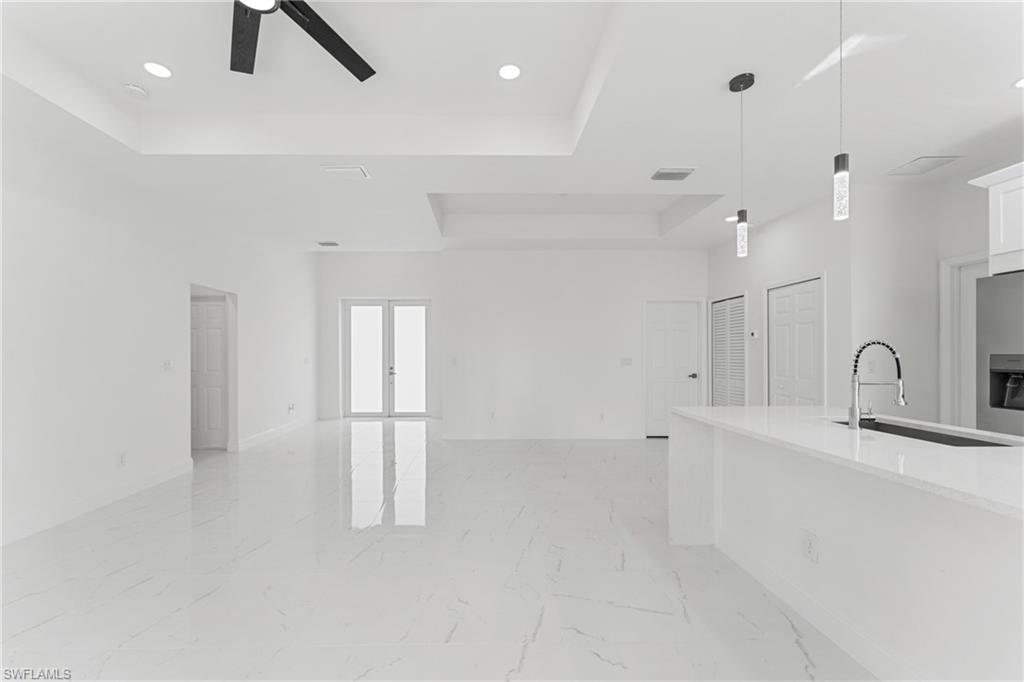 Kitchen with white cabinets, marble finish floor, a tray ceiling, and open floor plan