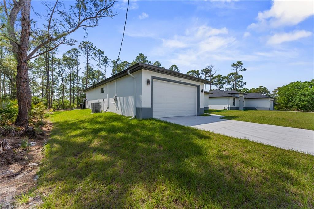 View of side of property featuring central AC, a yard, concrete driveway, and stucco siding