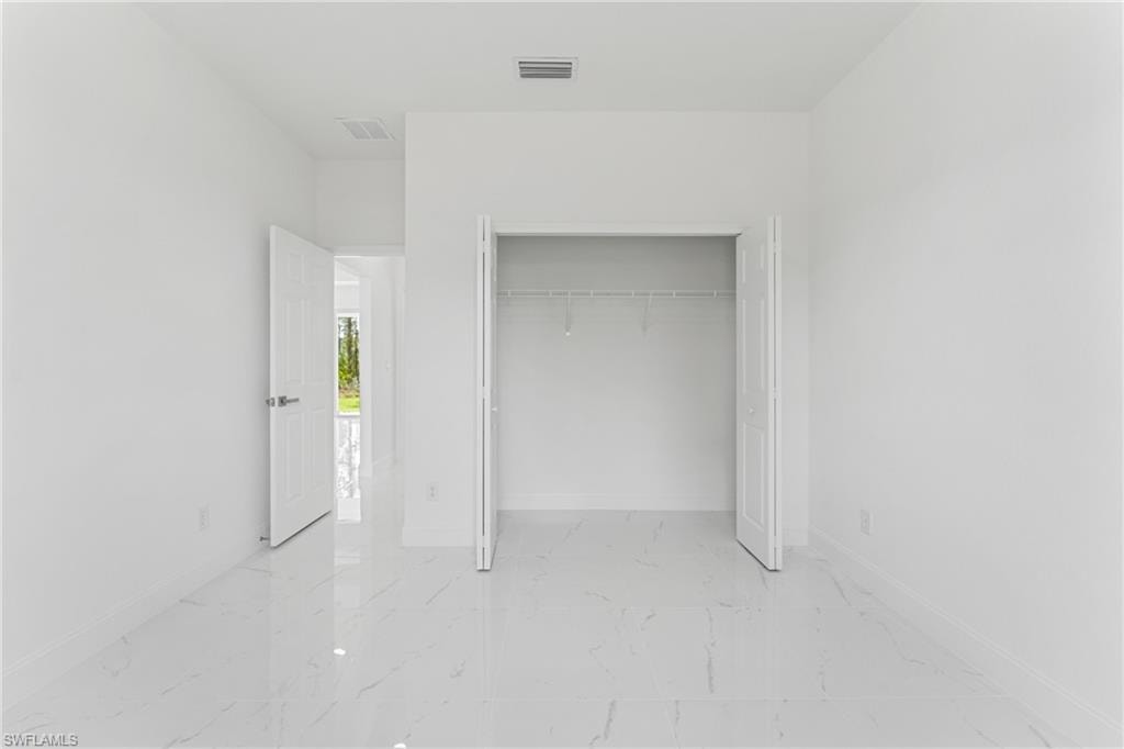 Unfurnished bedroom with marble finish floor, visible vents, and baseboards