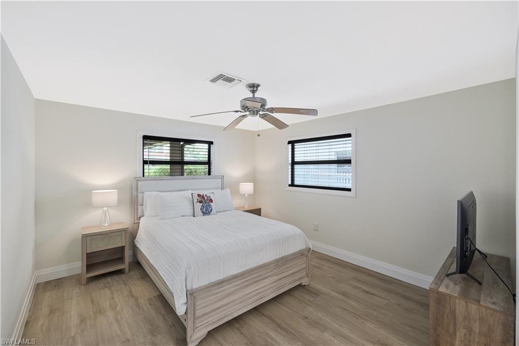 Bedroom featuring multiple windows, light wood-type flooring, and ceiling fan