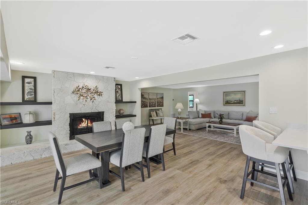 Dining space featuring a stone fireplace, light wood finished floors, and recessed lighting