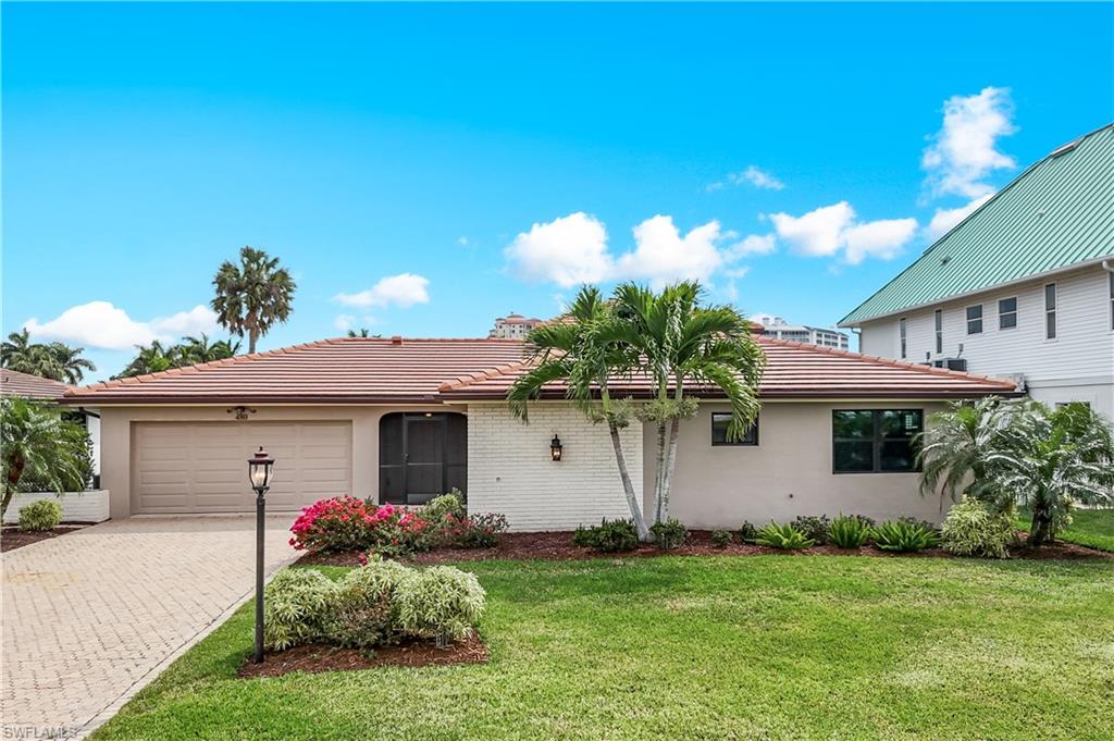 View of front facade with decorative driveway, a garage, a tiled roof, and stucco siding