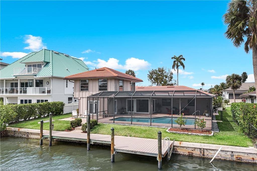 Rear view of property featuring glass enclosure, a water view, an outdoor pool, and a sunroom