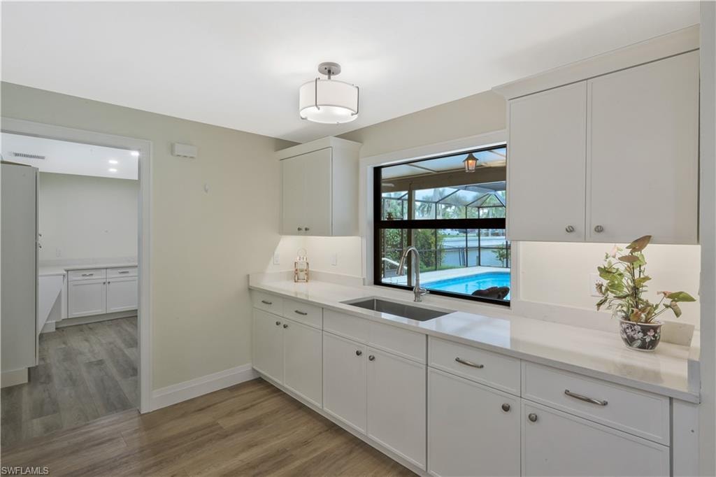 Kitchen with white cabinetry, light wood-style floors, and pendant lighting