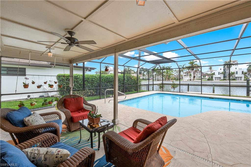 Outdoor pool featuring a sunroom, a patio, outdoor seating, a water view, and glass enclosure