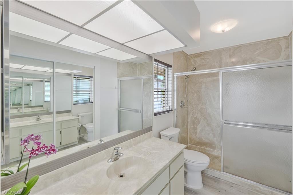Bathroom with vanity, a stall shower, and light wood-style flooring