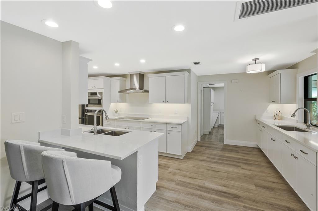 Kitchen featuring white cabinets, a breakfast bar, a peninsula, recessed lighting, and light wood finished floors