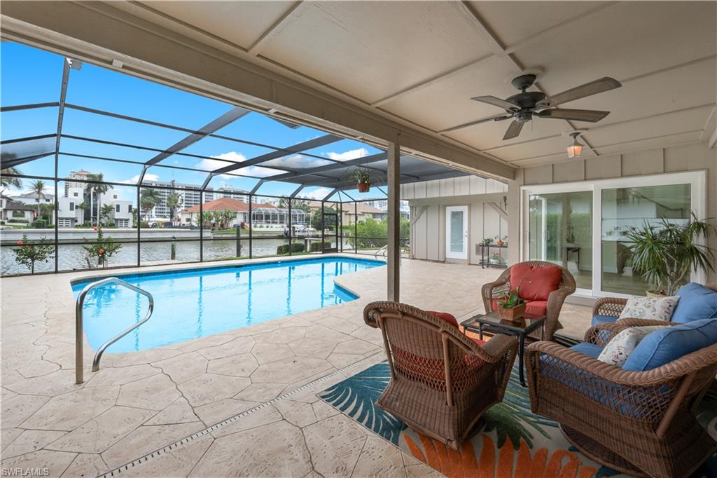 Swimming pool featuring a patio area, a sunroom, a lanai, a residential view, and a water view