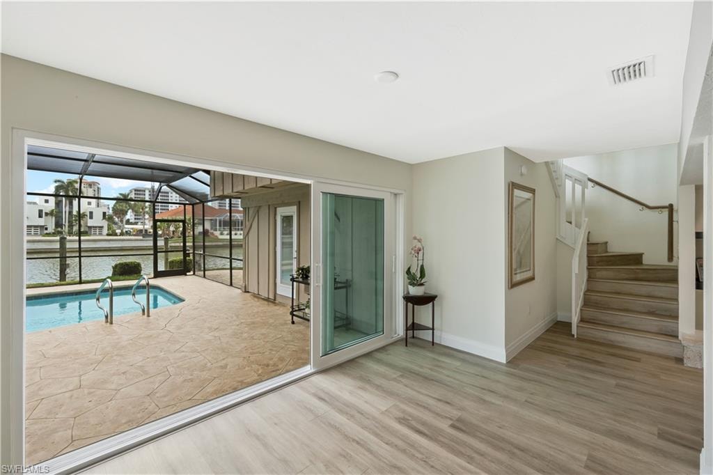 Entryway with a sunroom, wood finished floors, a water view, and a residential view