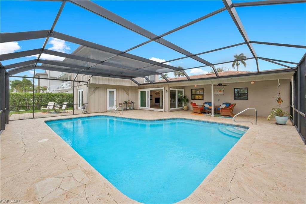 Outdoor pool featuring a sunroom, glass enclosure, a patio, and outdoor lounge area