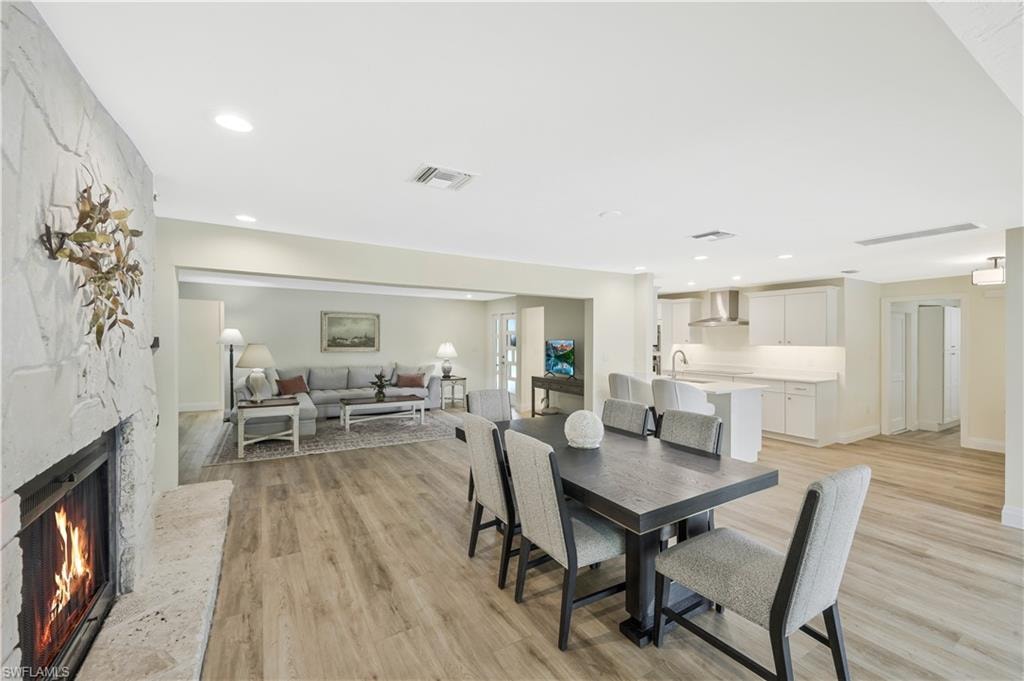 Dining area with a stone fireplace, light wood-type flooring, and recessed lighting