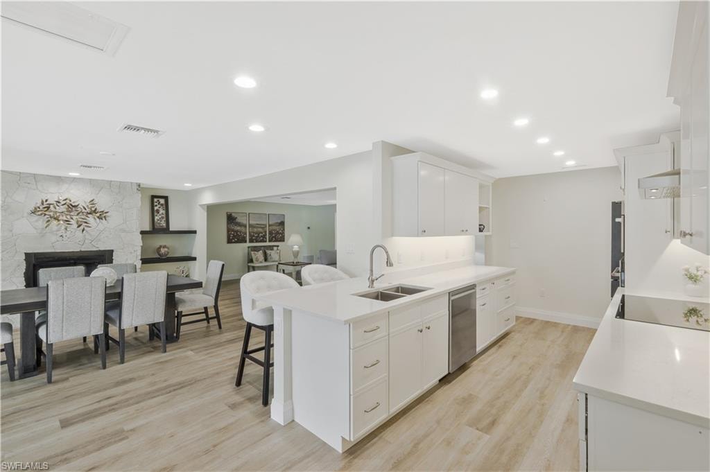 Kitchen with a peninsula, open floor plan, white cabinets, a kitchen breakfast bar, and open shelves