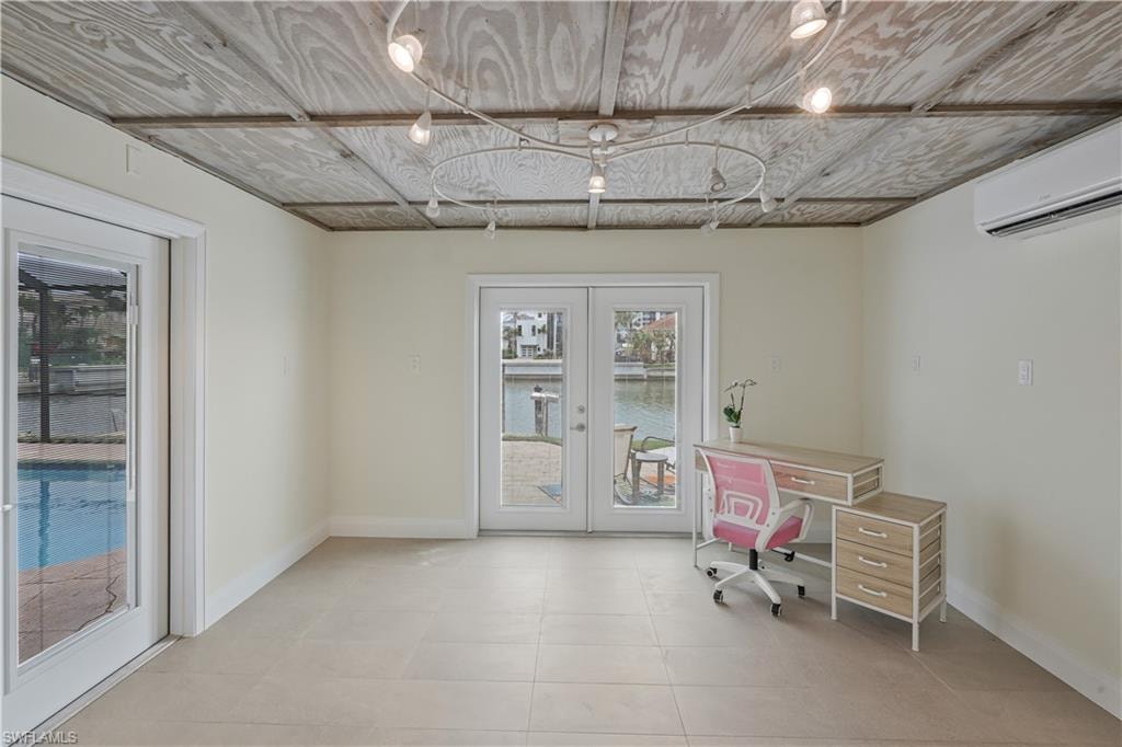 Unfurnished office with french doors, a wall mounted mini split, and light tile patterned flooring