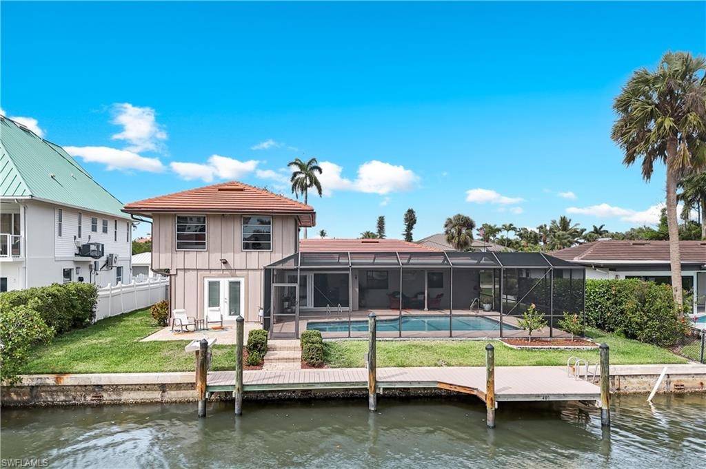 Rear view of property with a water view, glass enclosure, a sunroom, and an outdoor pool