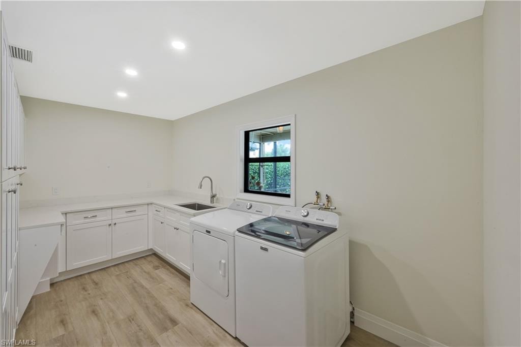 Laundry room with light wood-style floors, washer and dryer, cabinet space, and recessed lighting