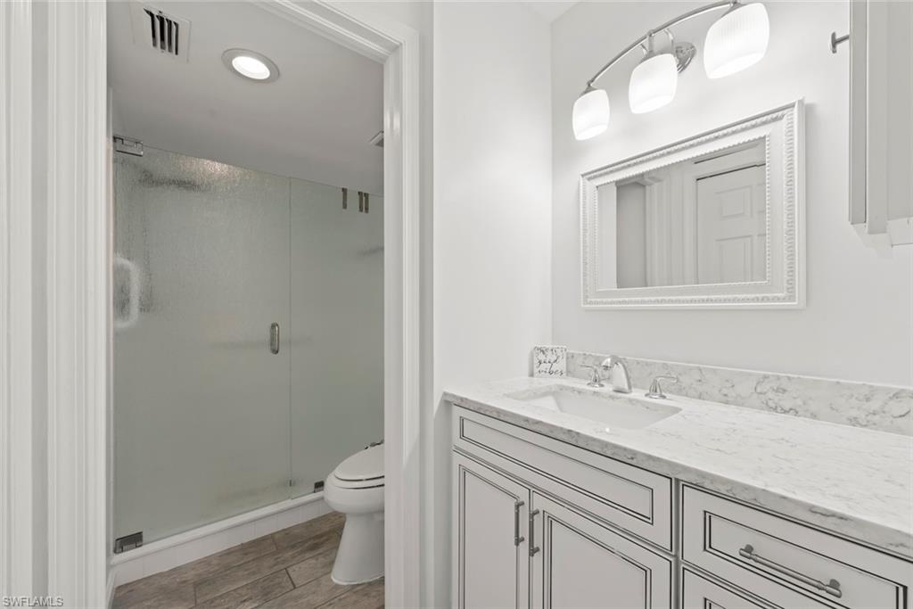 Full bathroom featuring vanity, a stall shower, light wood finished floors, and recessed lighting