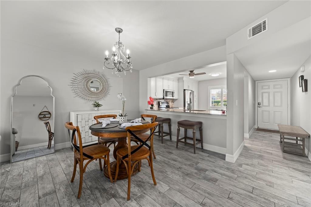 Dining area with a ceiling fan, light wood finished floors, and a chandelier