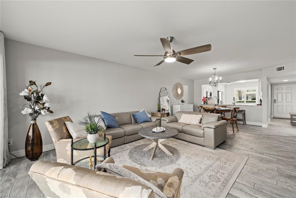 Living room with a ceiling fan, light wood-type flooring, and a chandelier