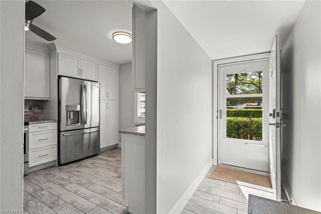Kitchen with wood finish floors, stainless steel fridge, white cabinets, a ceiling fan, and healthy amount of natural light